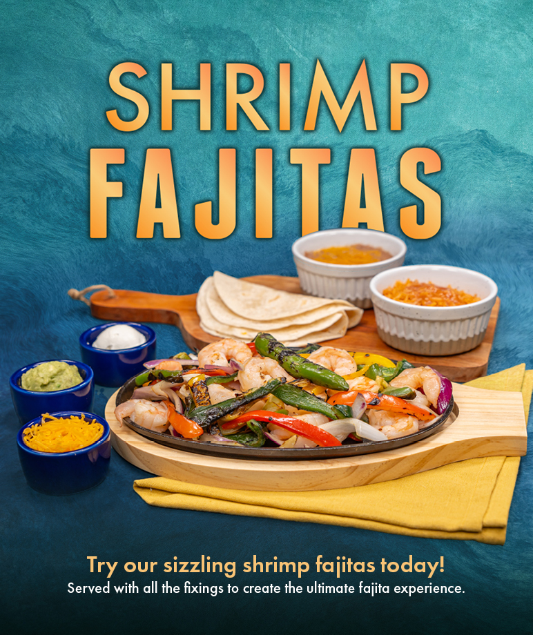 The image displays a vibrant and colorful serving of shrimp fajitas with the inviting text "Try our sizzling SHRIMP FAJITAS" placed above. The fajitas are presented on a skillet with shrimp and assorted grilled vegetables. Accompanying the main dish are sides of shredded cheese, sour cream, guacamole, and rice, with tortillas on the side, all laid out on a wooden board over a blue textured background. The image is likely intended for use as an advertisement or menu promotion.